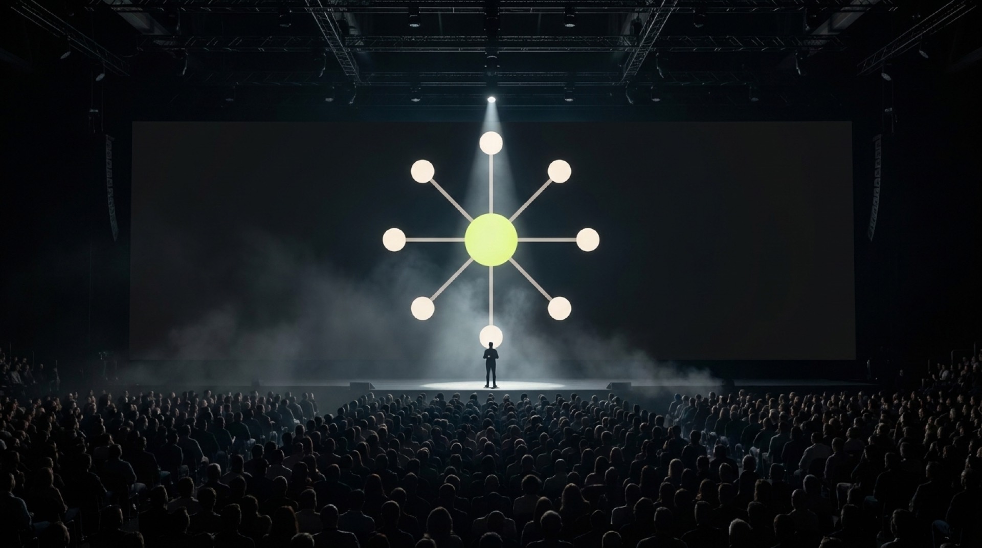 A speaker on a keynote stage beneath the IAW hub mark — brand visual